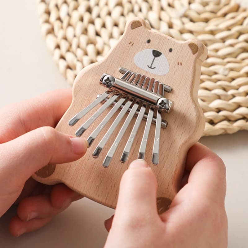 Kalimba 8 lames en bois découpé en forme d'ourson tenu dans une main